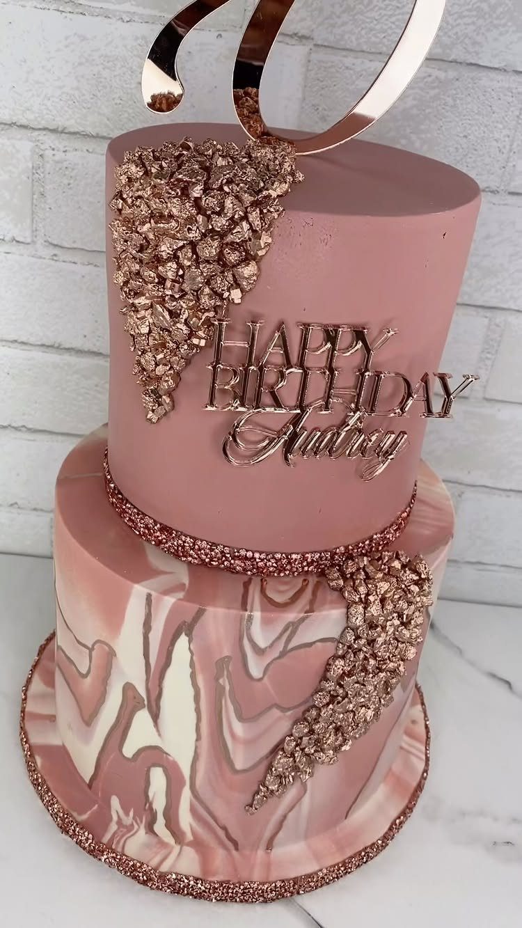 Two-tier rose gold birthday cake with marble patterns and sparkling crystal decorations.