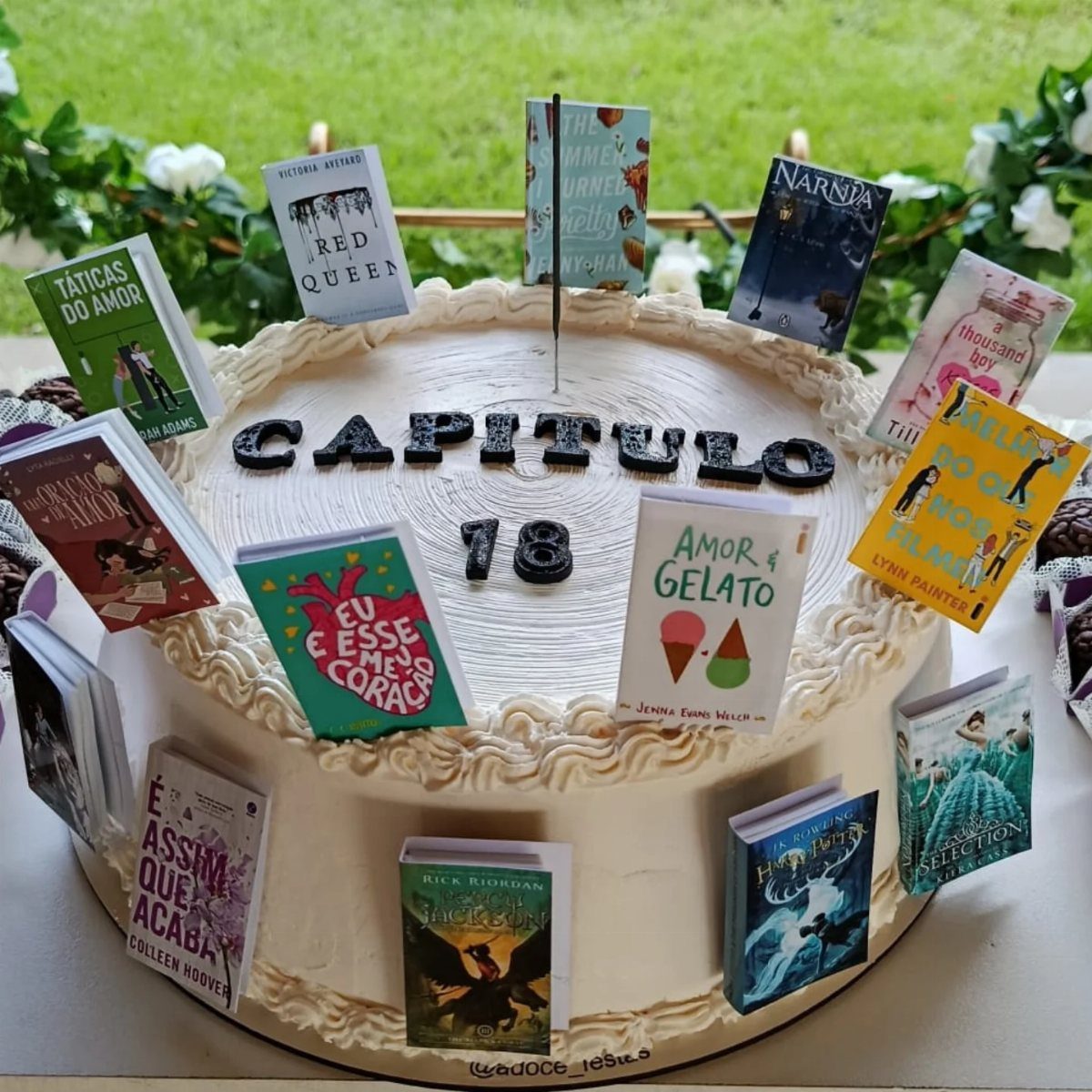 White frosted cake decorated with miniature book covers and the text Capitulo 18.
