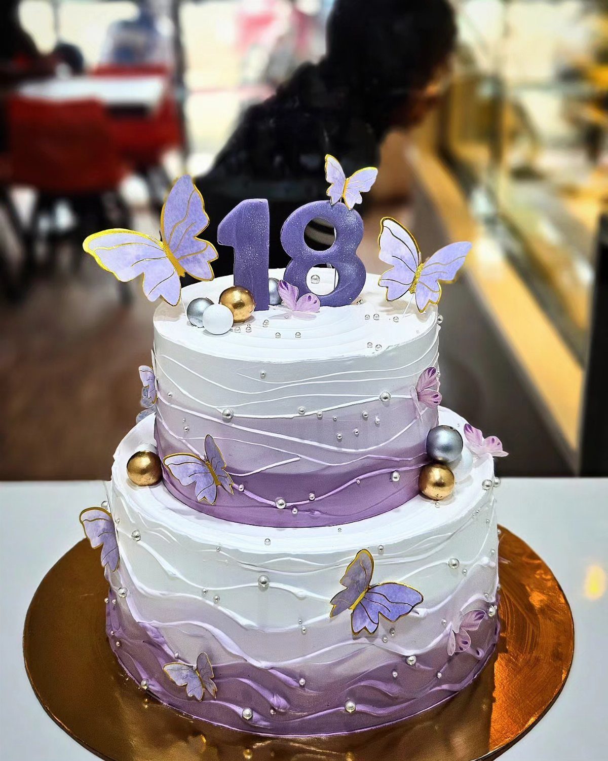 Two-tier purple ombre cake with butterflies and a purple 18 birthday topper.