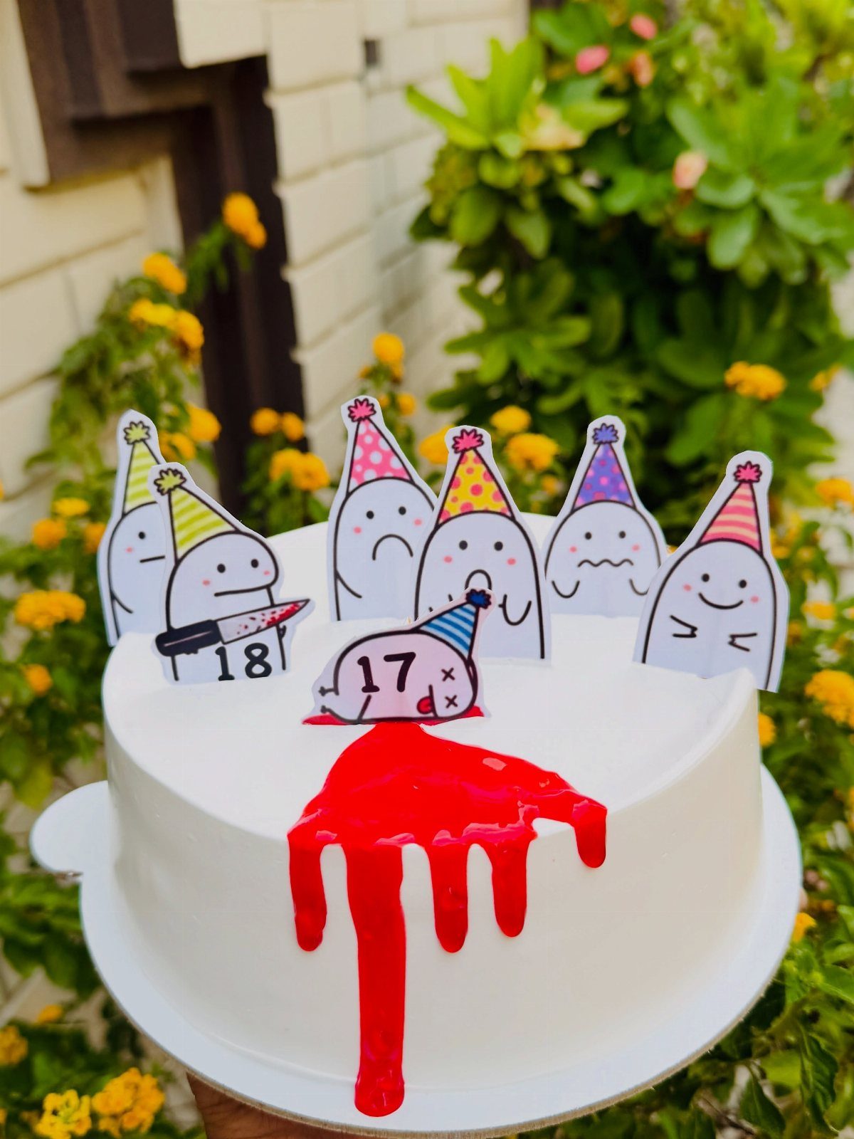 White cake with red drip and cartoon ghost toppers celebrating an 18th birthday.