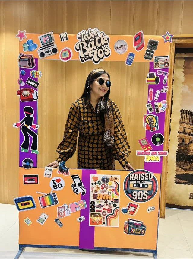 Woman posing in a retro-themed photo frame decorated with 70s and 90s stickers.