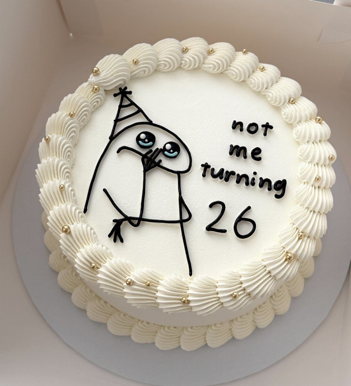 White frosted birthday cake with a character drawing and text saying not me turning 26