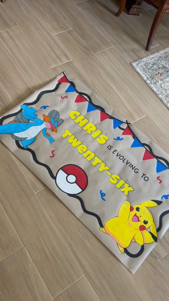 Hand-painted Pokemon themed birthday banner for a twenty-sixth birthday on a wooden floor