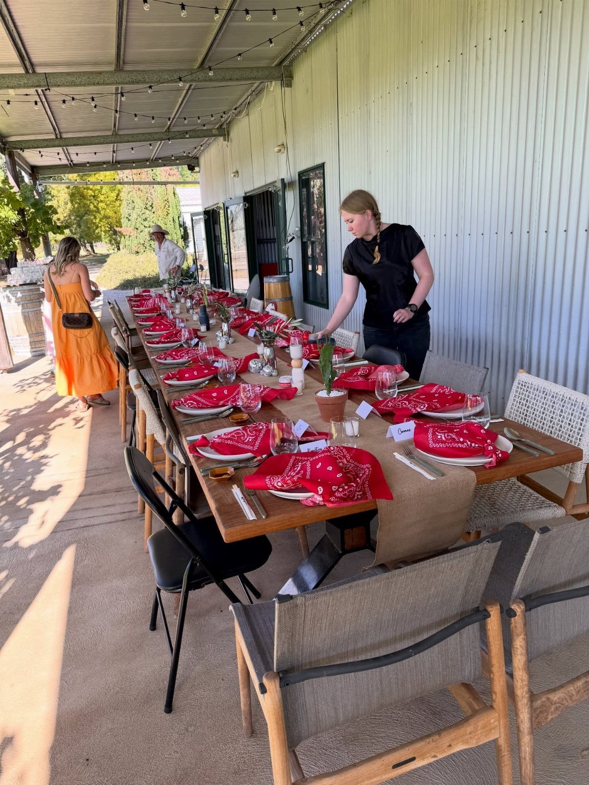 Outdoor party table set with red bandanas and white plates under a porch