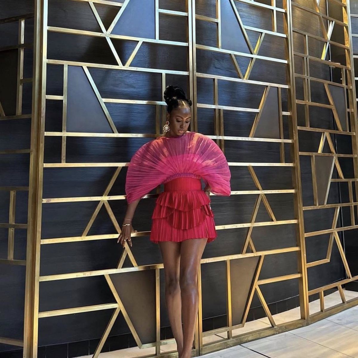 Woman wearing a bright pink pleated crop top and matching tiered mini skirt
