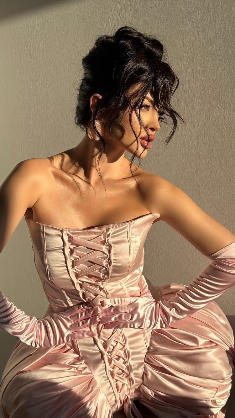 Woman wearing a light pink satin corset dress and matching opera gloves.