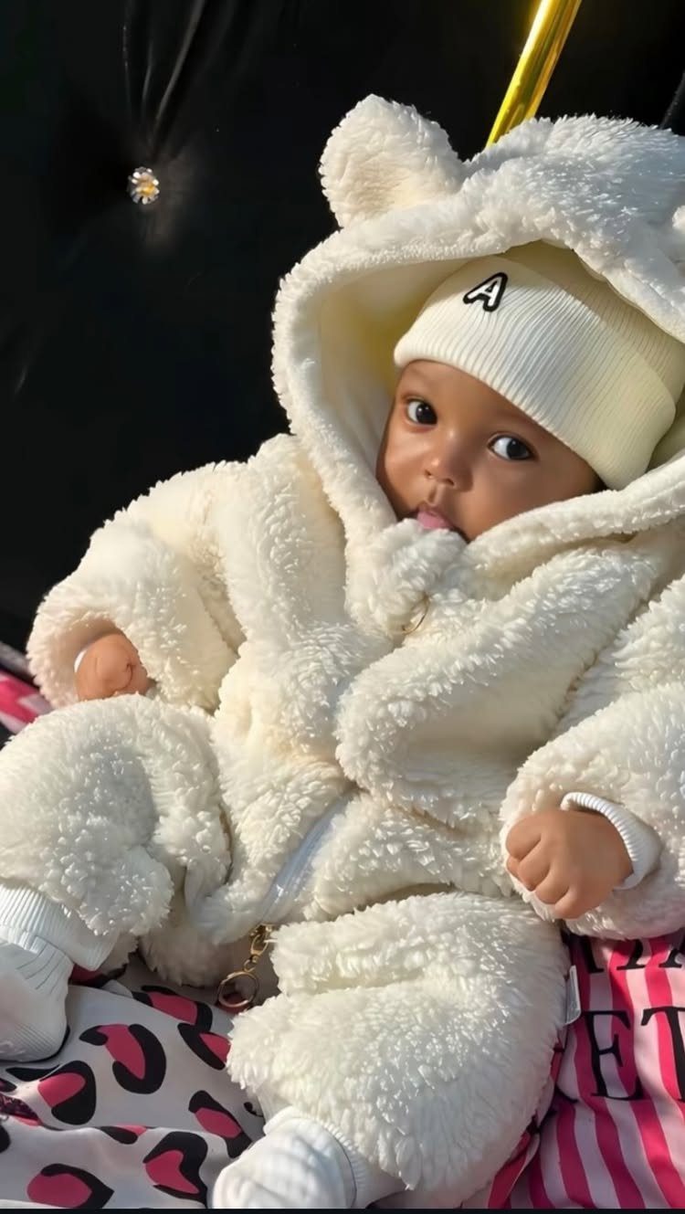 Baby wearing a white fluffy hooded zip romper and a matching beanie hat.