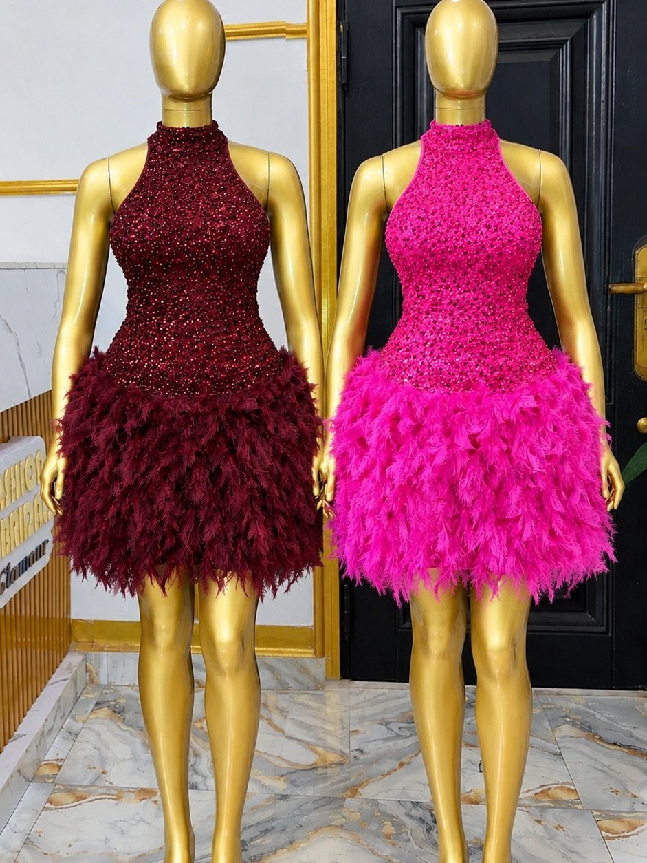 Two gold mannequins wearing sequined halter dresses with fluffy feather trim skirts.