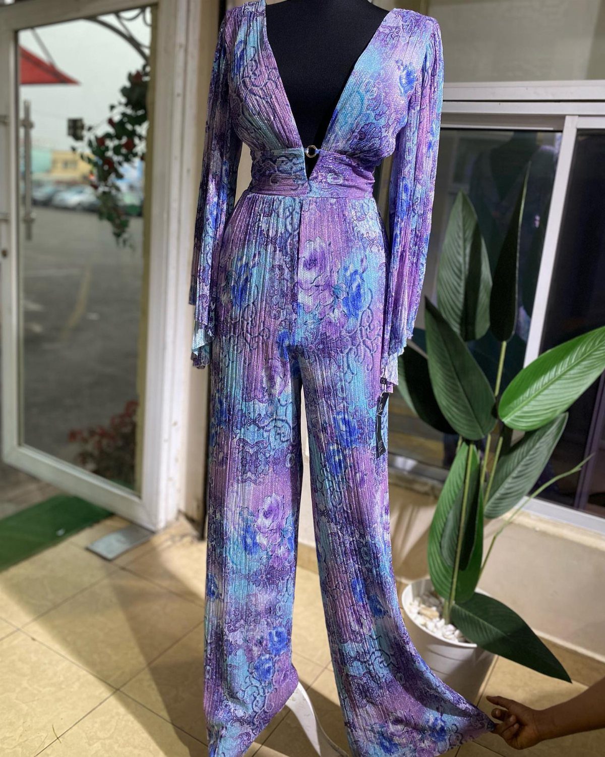 Purple and blue patterned jumpsuit with a deep V-neck on a black mannequin.