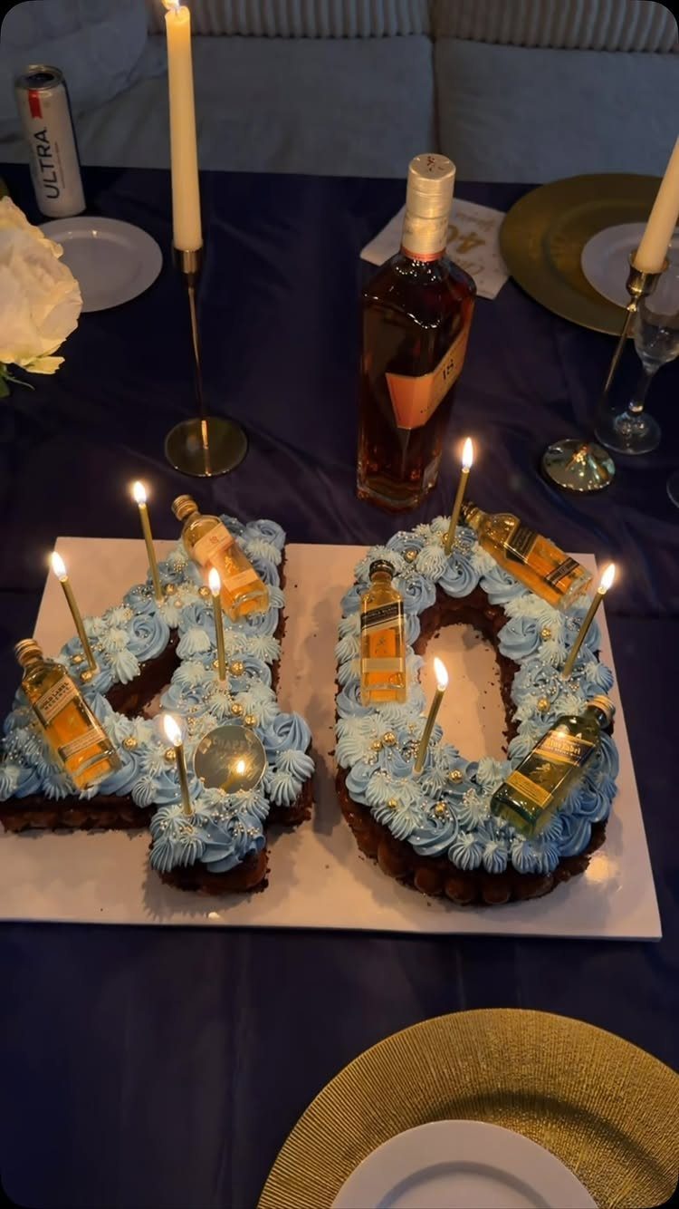 Number 40 chocolate cake with blue frosting and miniature liquor bottles on a table