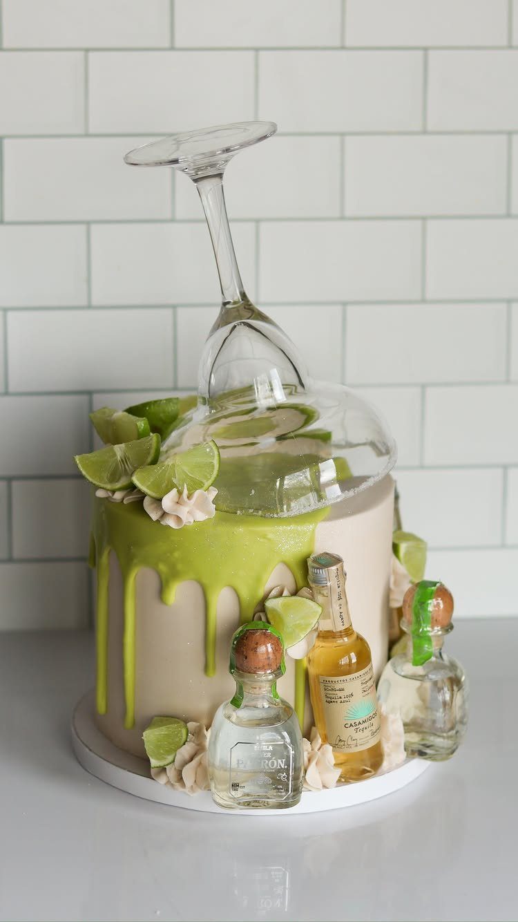 Margarita themed cake with lime green drip, tequila bottles, and a tilted glass.