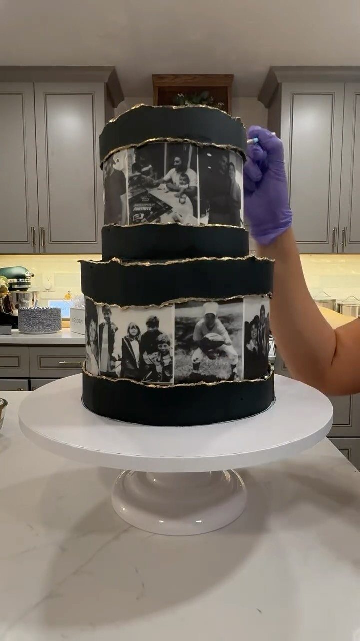Two-tier black cake decorated with edible black and white photos and gold accents.