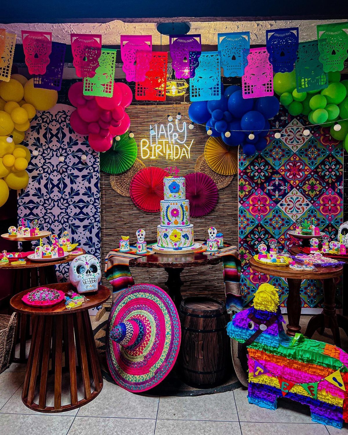 Mexican themed birthday party setup with a colorful piñata, cake, and skull decorations.