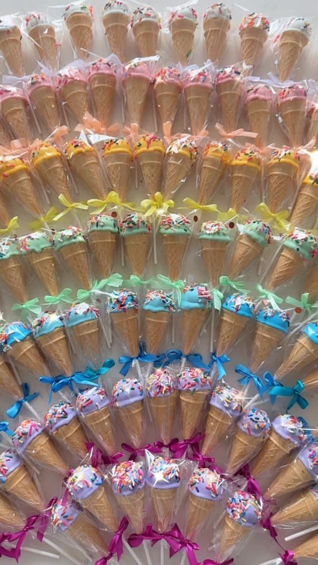 Miniature ice cream cake pops wrapped in plastic with colorful ribbons and sprinkles.