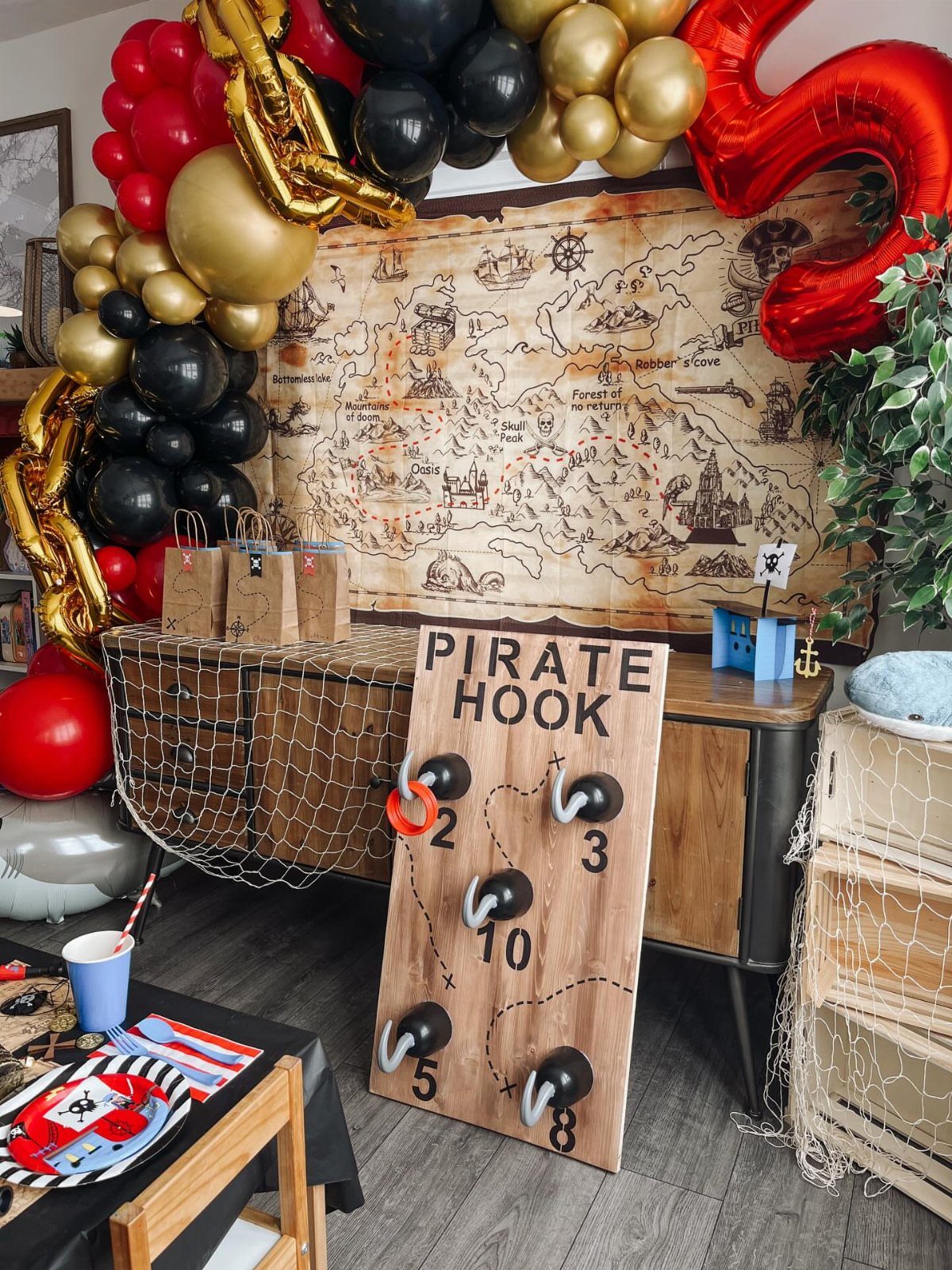 Pirate party decorations with a balloon arch, treasure map, and pirate hook game.