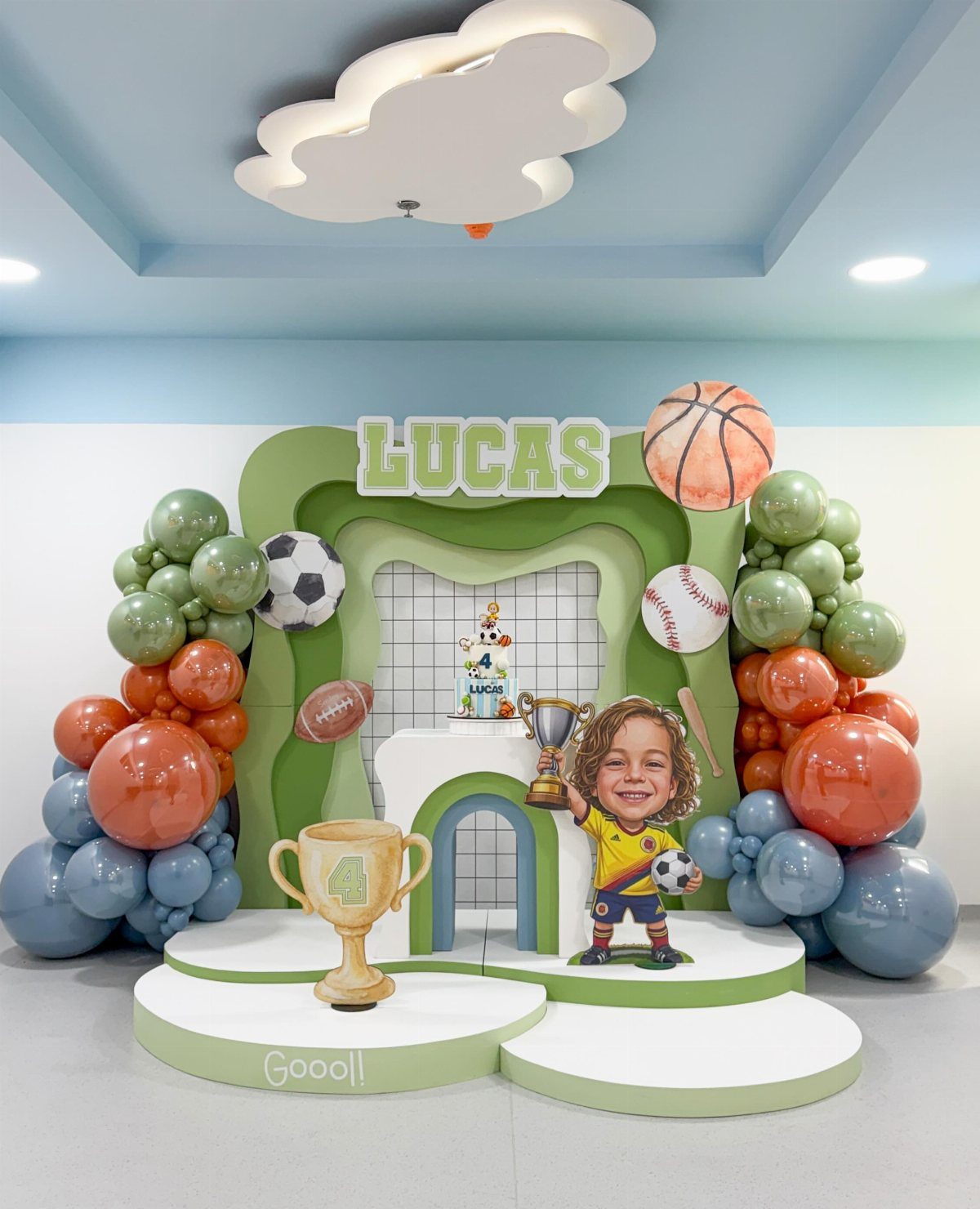Sports themed birthday party decorations with balloons, trophies, and various sports balls.