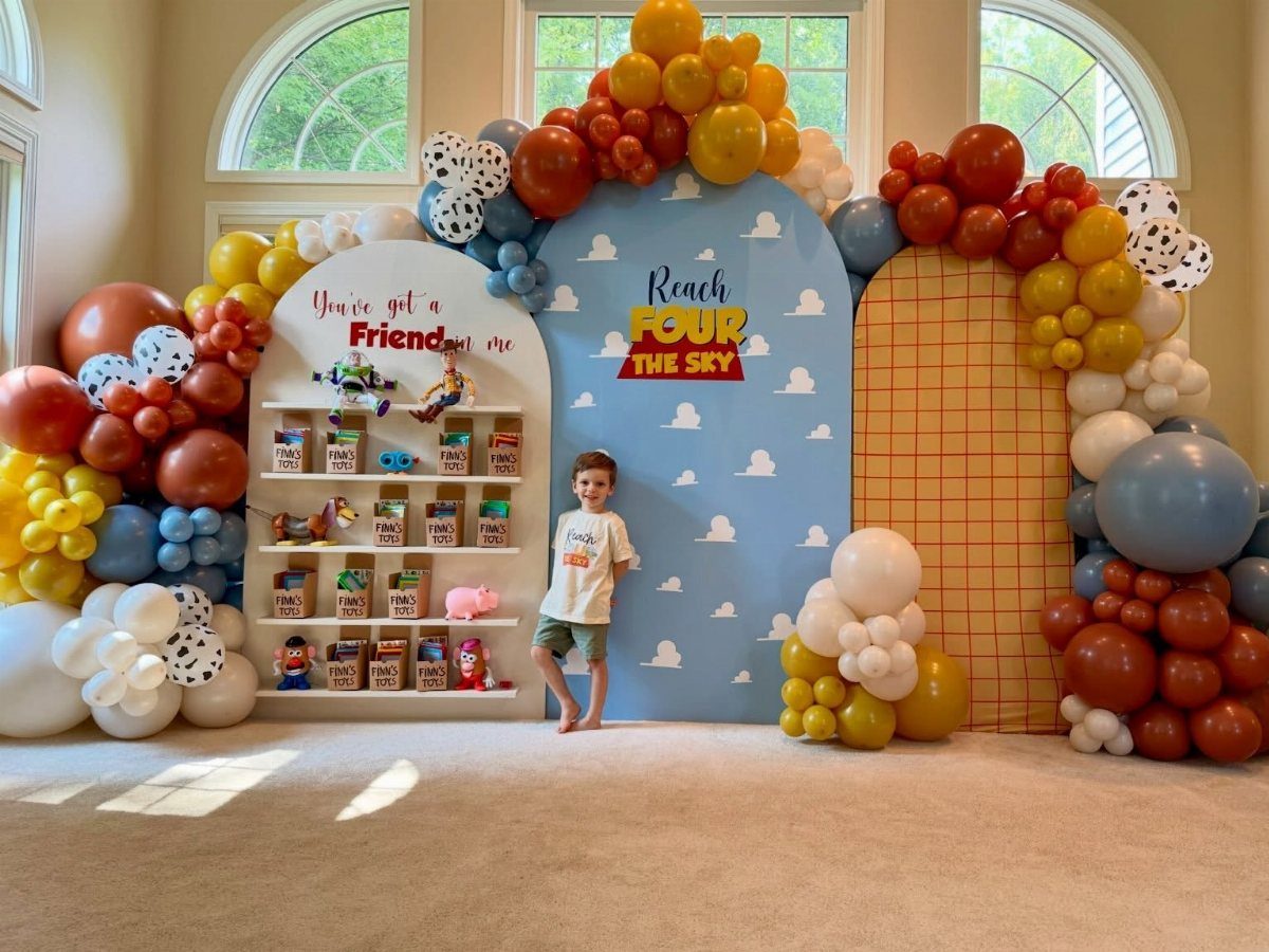 Young boy standing in front of a Toy Story themed birthday party backdrop.