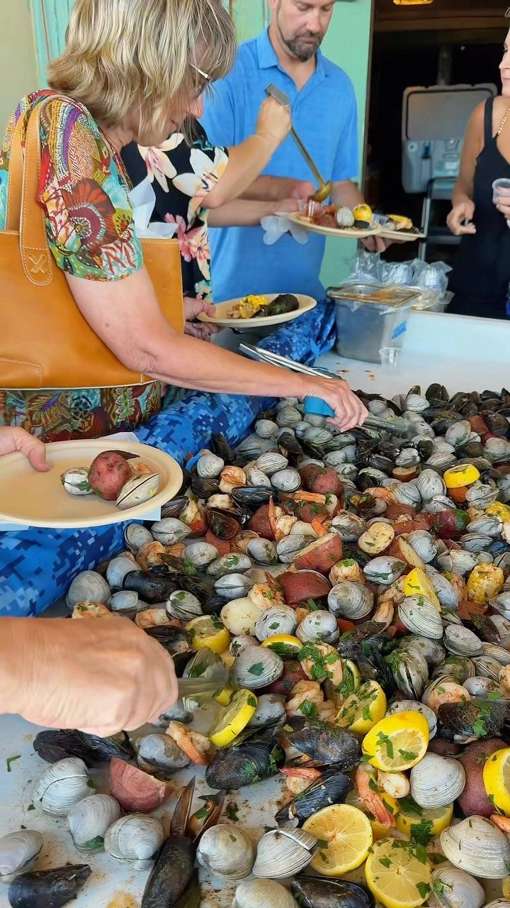 Seafood feast with clams, mussels, corn, and potatoes served at a casual gathering.