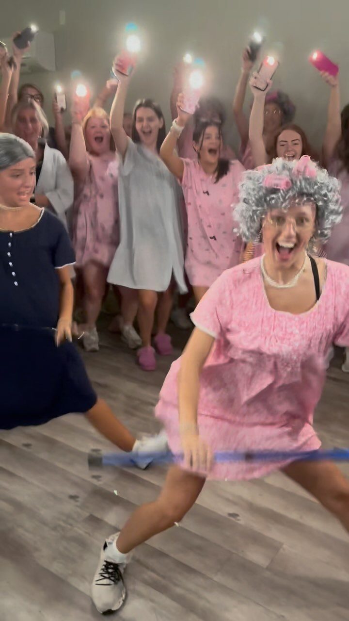 Women wearing grey curly wigs and nightgowns posing for a themed party photo.