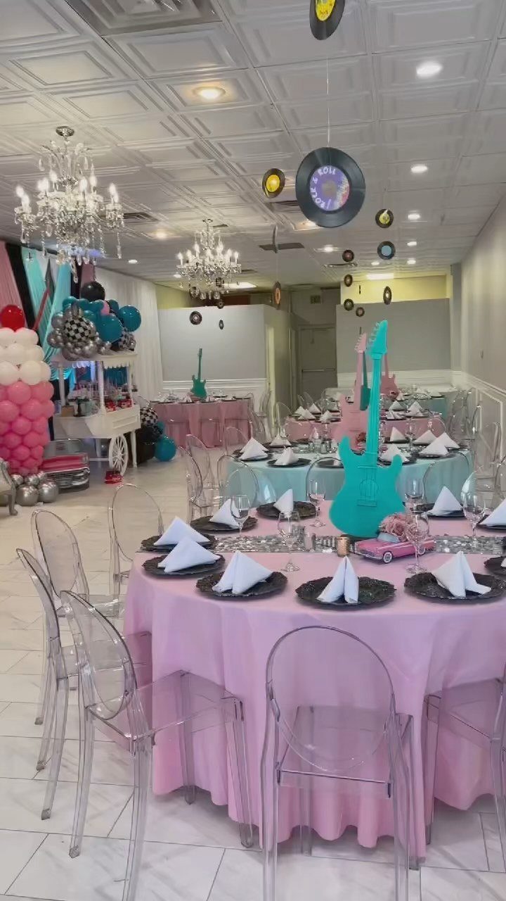 Party room decorated with pink tablecloths, hanging vinyl records, and a turquoise guitar.