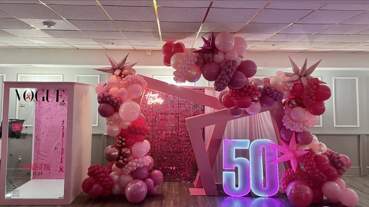Pink and purple balloon arches with a glowing number 50 sign and backdrop.