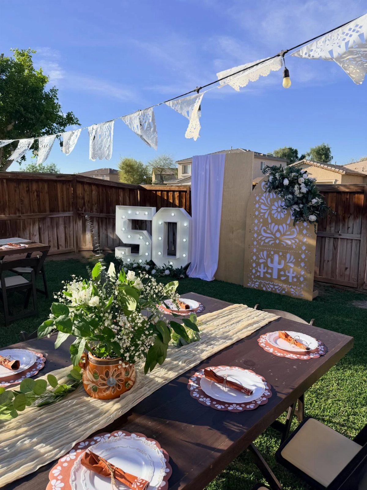 Outdoor party table with floral centerpiece and large illuminated 50 numbers in background