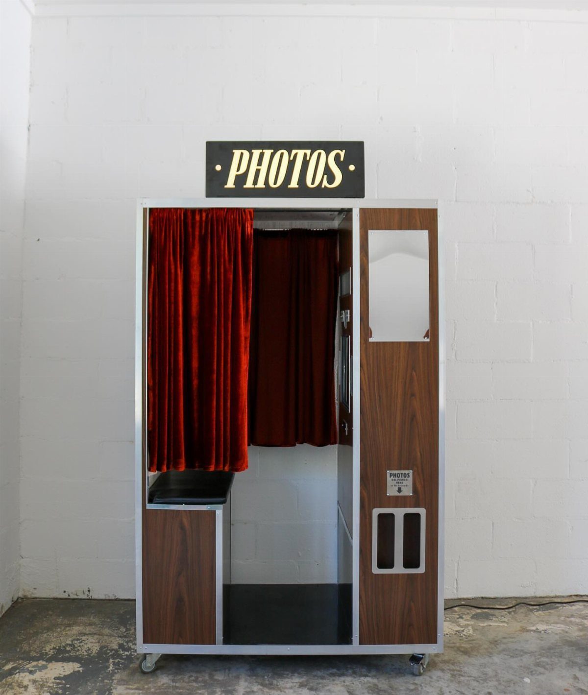 Vintage photo booth with red velvet curtains and a gold PHOTOS sign.