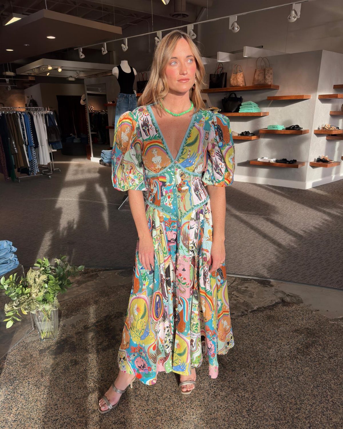 Woman in a colorful patterned puff sleeve midi dress standing in a boutique