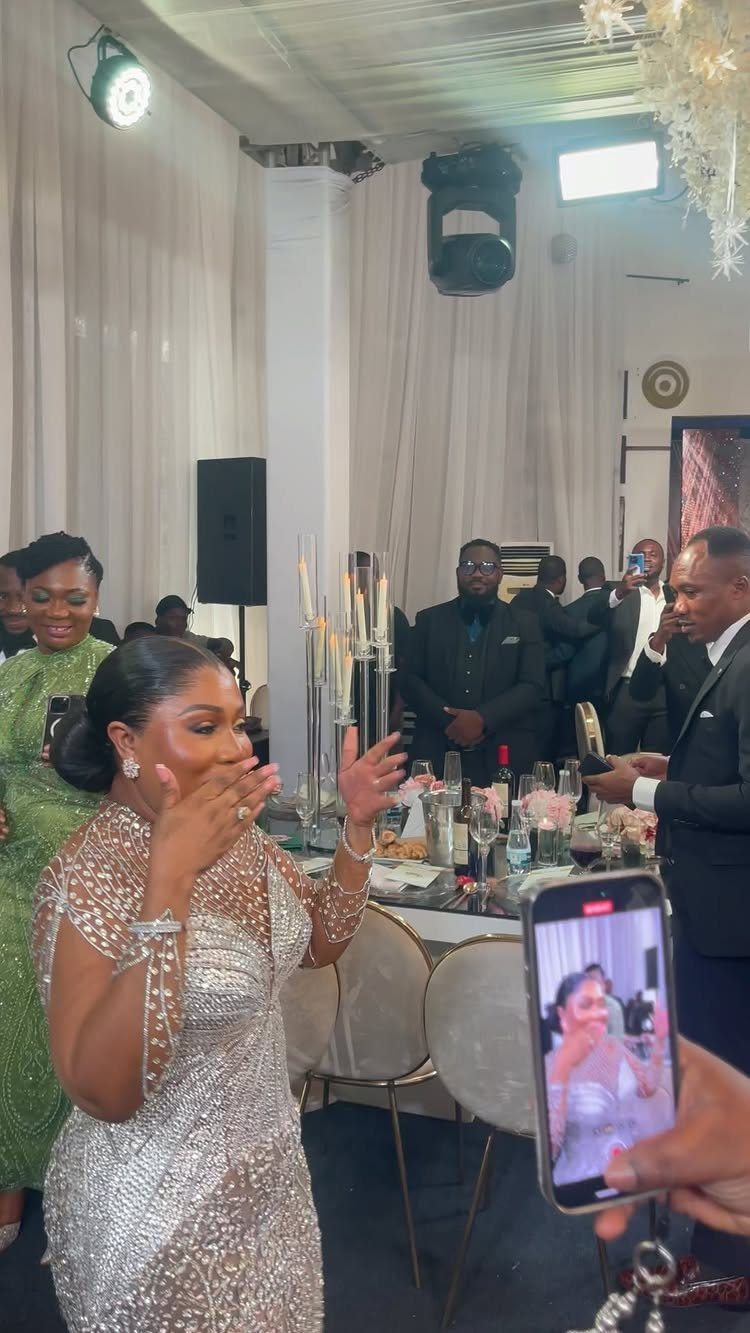 Woman in a sparkling silver sequined dress reacting with surprise at a formal party.
