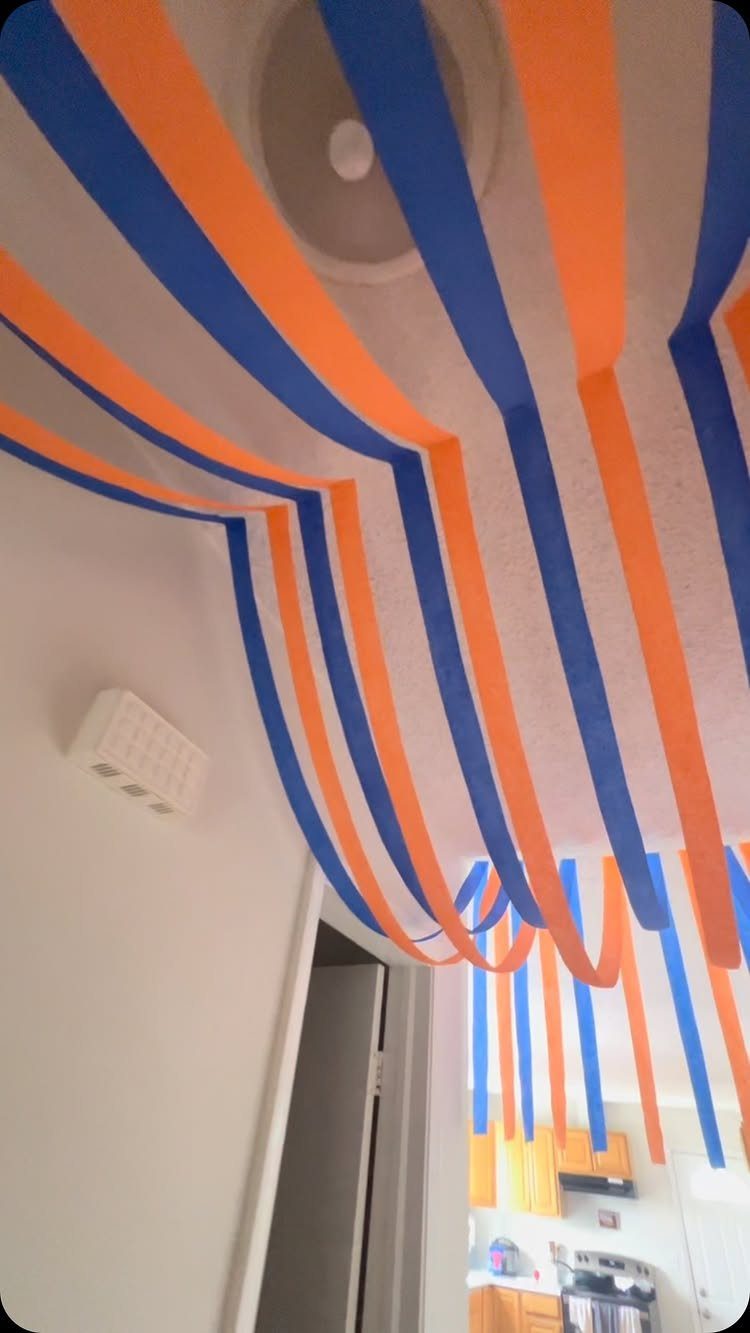 Blue and orange paper streamers draped across a white ceiling in a room.
