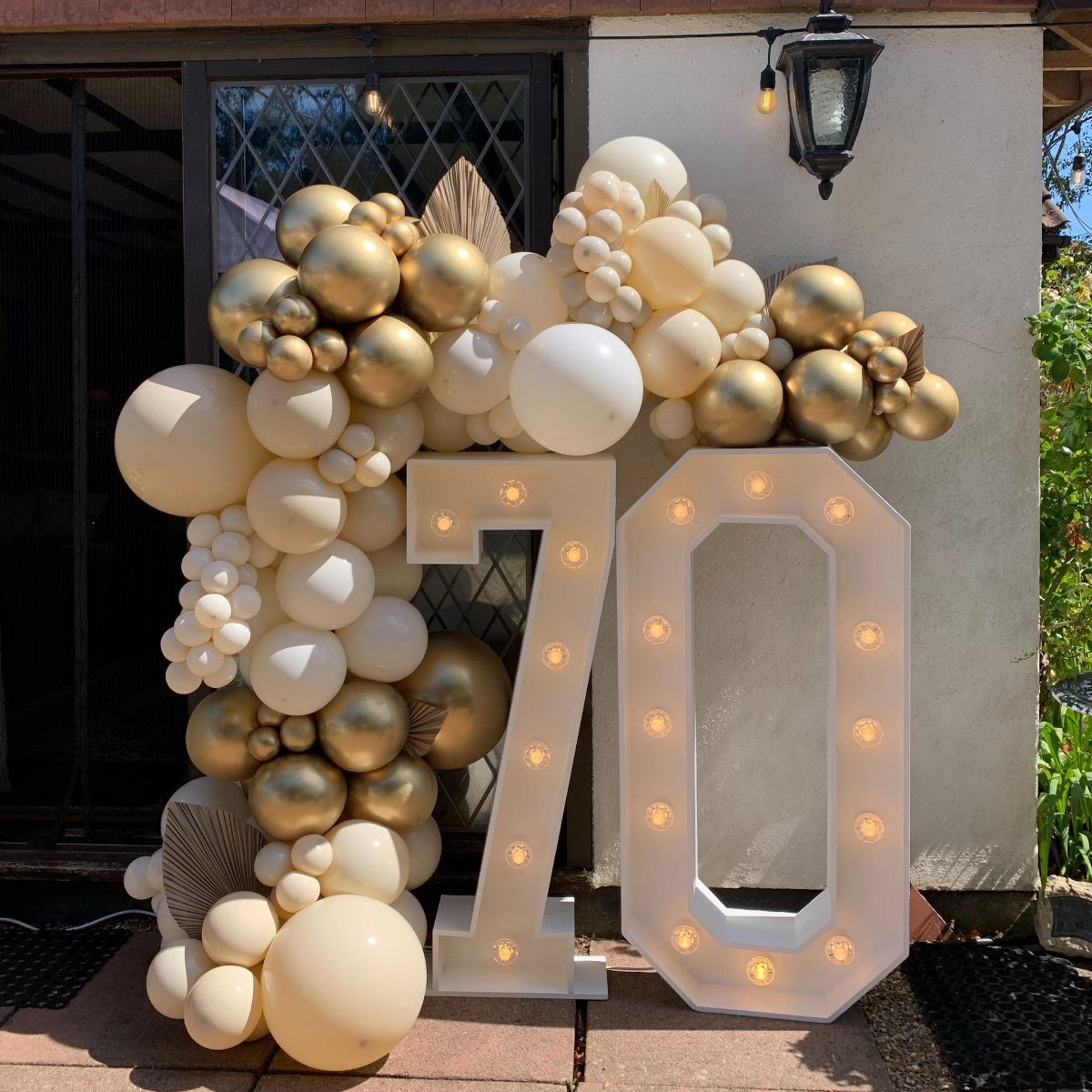 Large illuminated number 70 marquee signs surrounded by gold and white balloons.