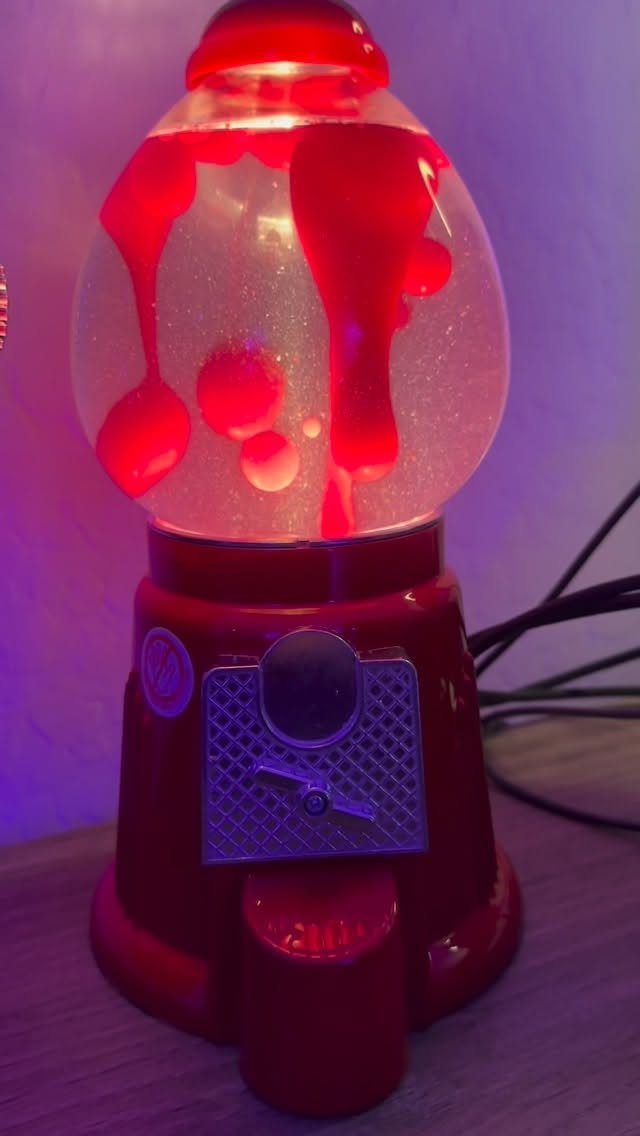 Red lava lamp with floating wax bubbles on a purple background