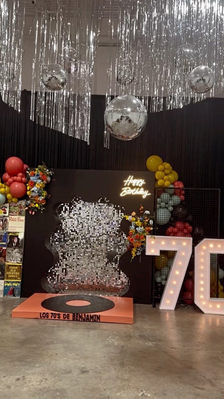 70th birthday party decorations featuring a sequin guitar, disco balls, and illuminated numbers.