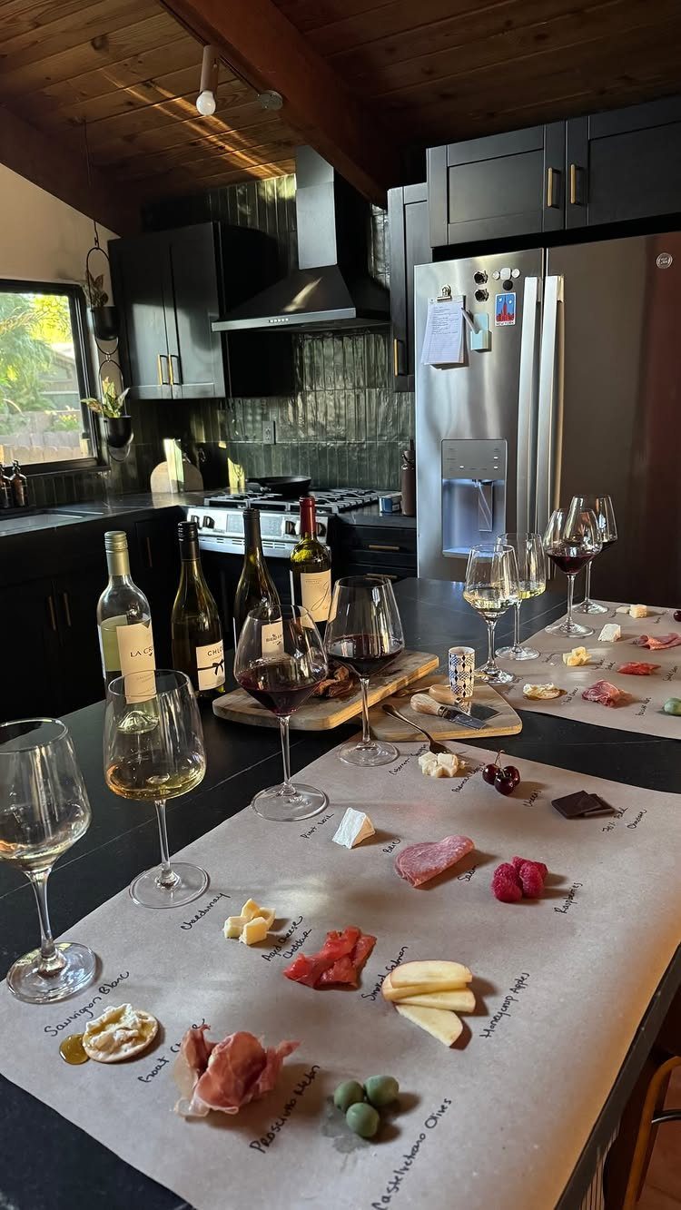Wine bottles and glasses with a charcuterie spread on a kitchen counter.