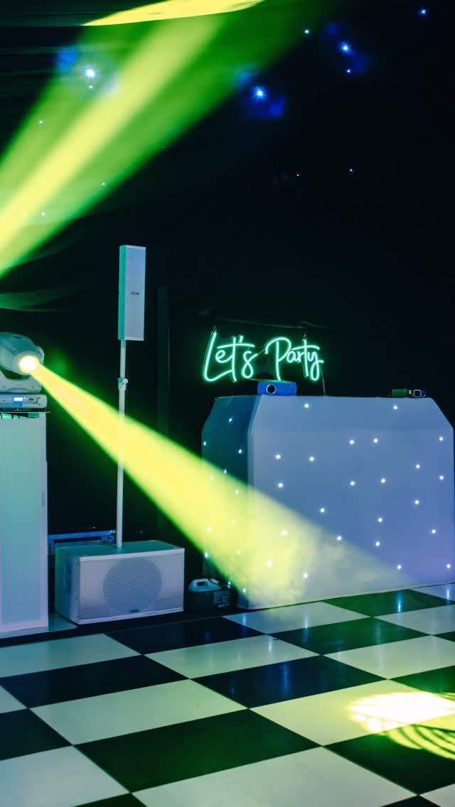 Checkered dance floor with yellow spotlights and a neon Let's Party sign.