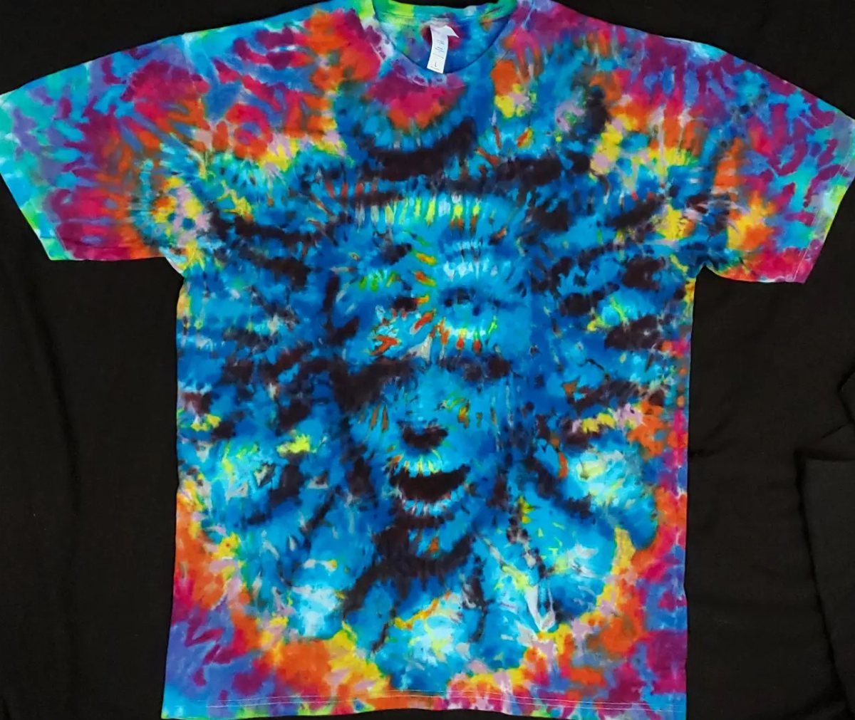 Tie-dye t-shirt with vibrant blue, yellow, and red patterns on black background