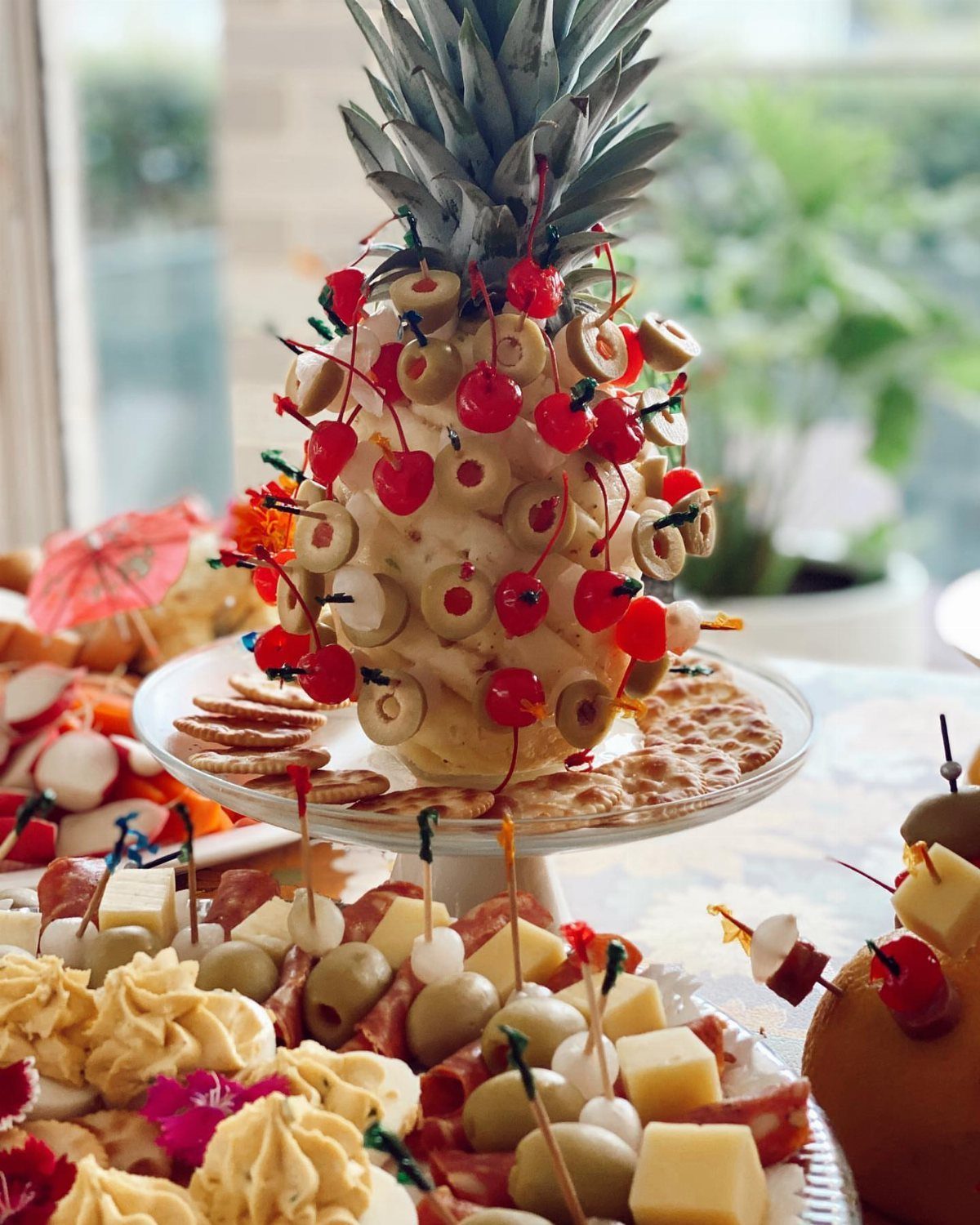 Pineapple cheese ball appetizer with olives and cherries on a party platter