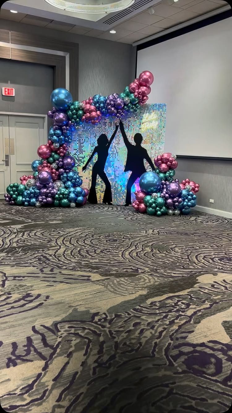 Sequin backdrop with dancing couple silhouettes framed by colorful balloons in a room.