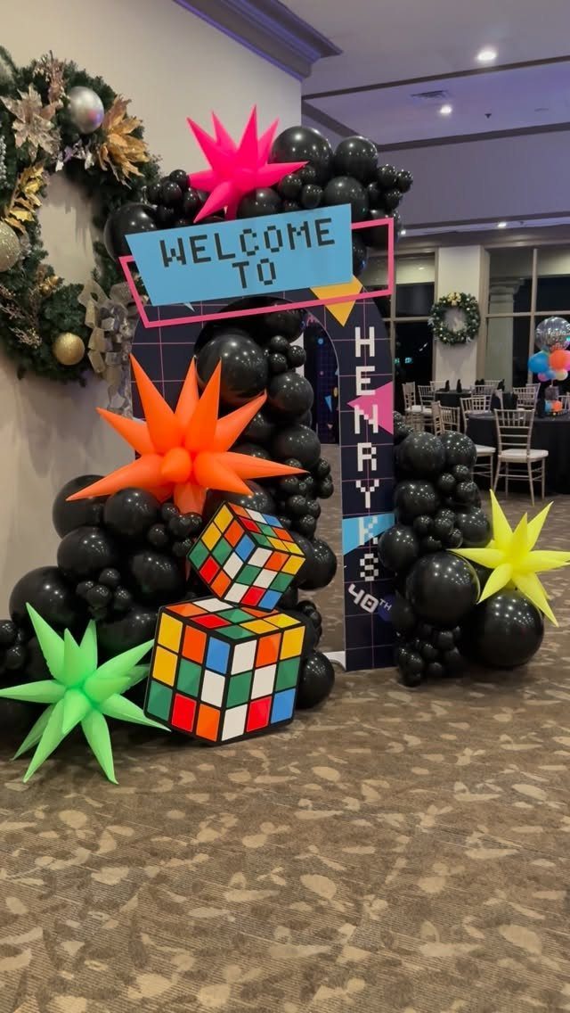 80s party decorations with black balloons, neon stars, and large Rubik's cubes.