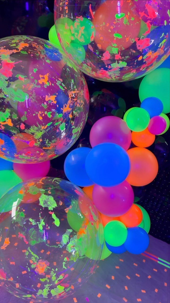 Neon glowing balloons in pink, blue, and green with confetti-filled clear balloons.