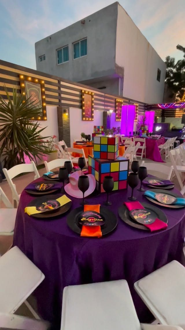 Purple party table with Rubik's Cube centerpieces and colorful napkins in an outdoor setting