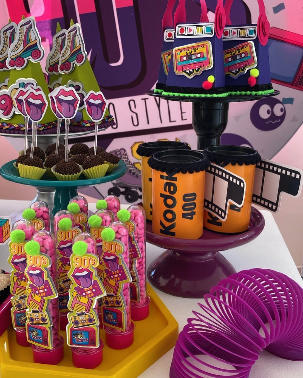 Nostalgic 90s party favors including candy tubes, film canisters, and a purple slinky.