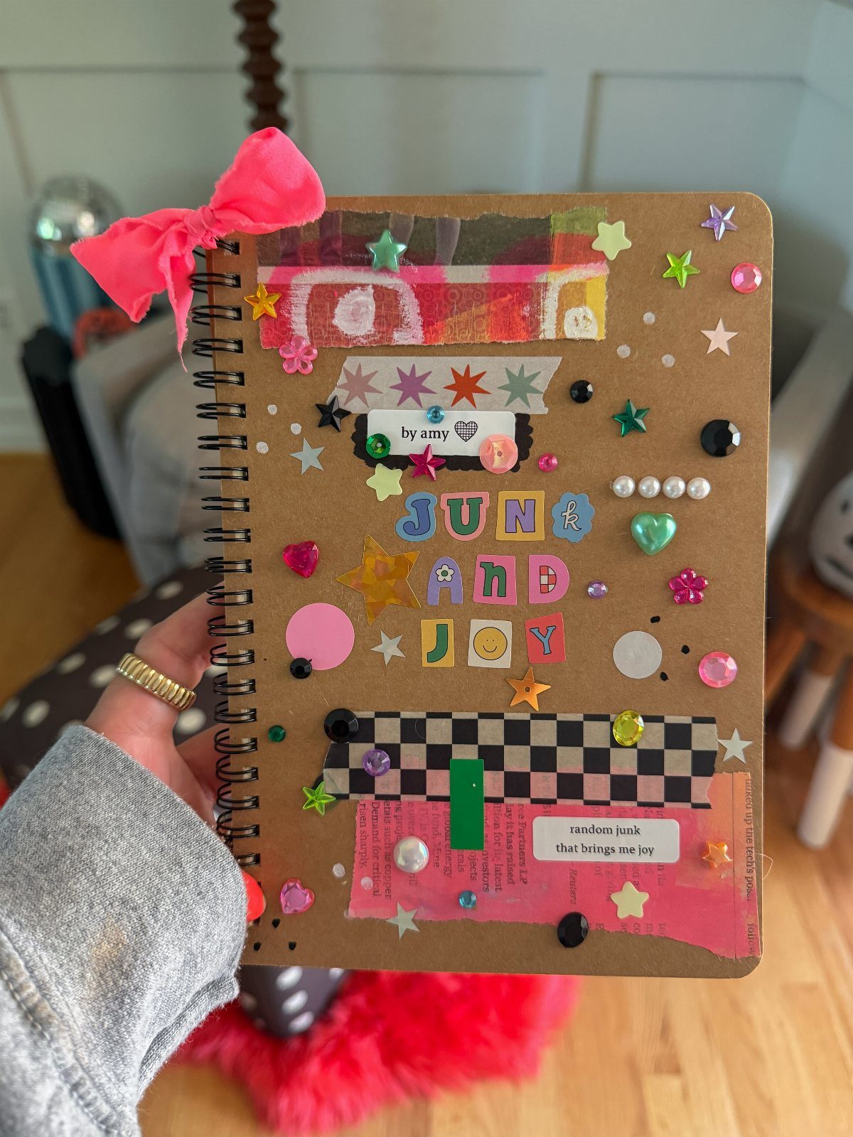 Decorated spiral notebook with colorful stickers, stars, and alphabet letters on brown cover.