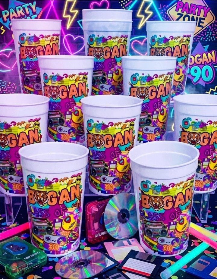 Colorful 90s themed party cups surrounded by CDs, floppy disks, and cassette tapes.