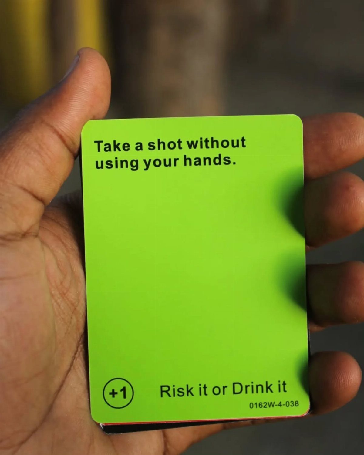 Green game card held in a hand with a drinking challenge instruction.