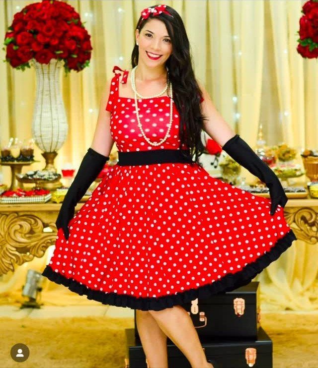 Woman in red polka dot 1950s dress with black gloves and pearl necklace.