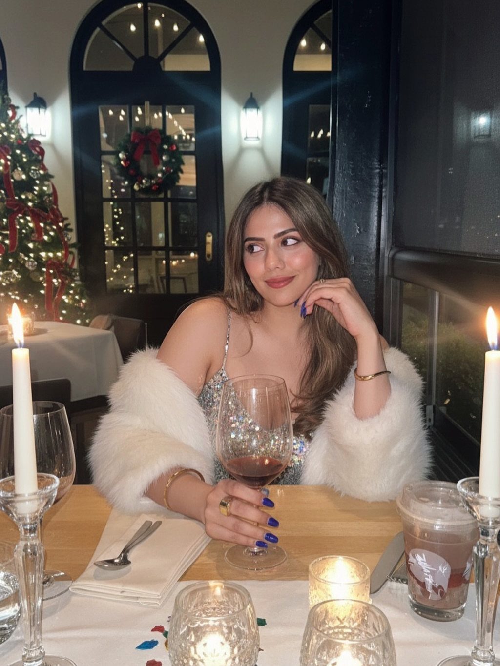Woman in sparkly dress and white fur shawl at a candlelit dinner table