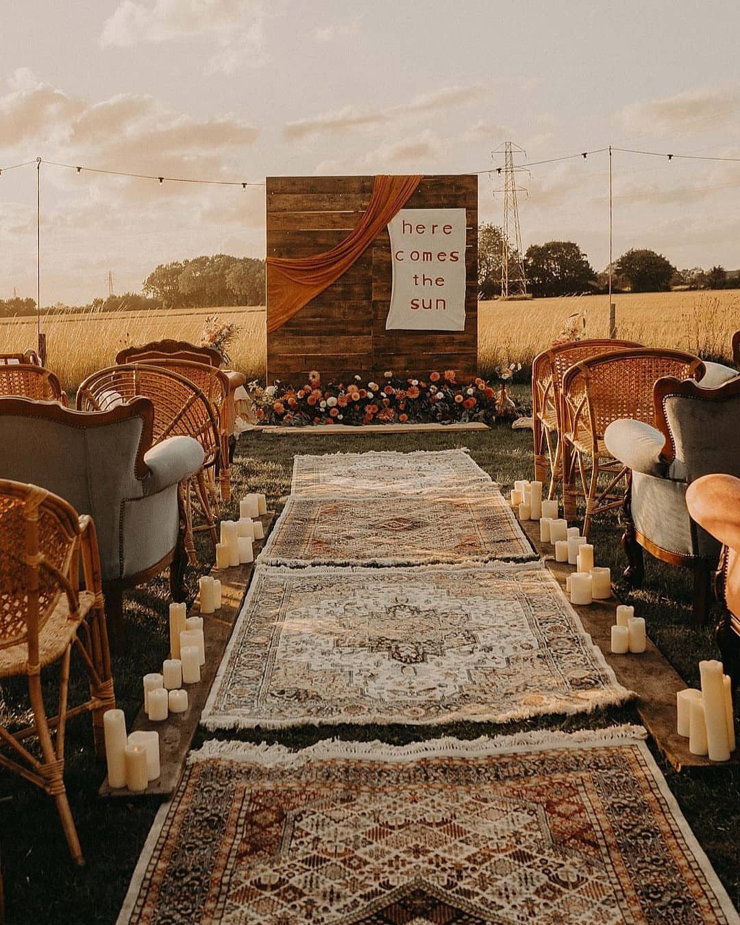 Rugged aisle runner lined with white pillar candles leading to a wooden backdrop.