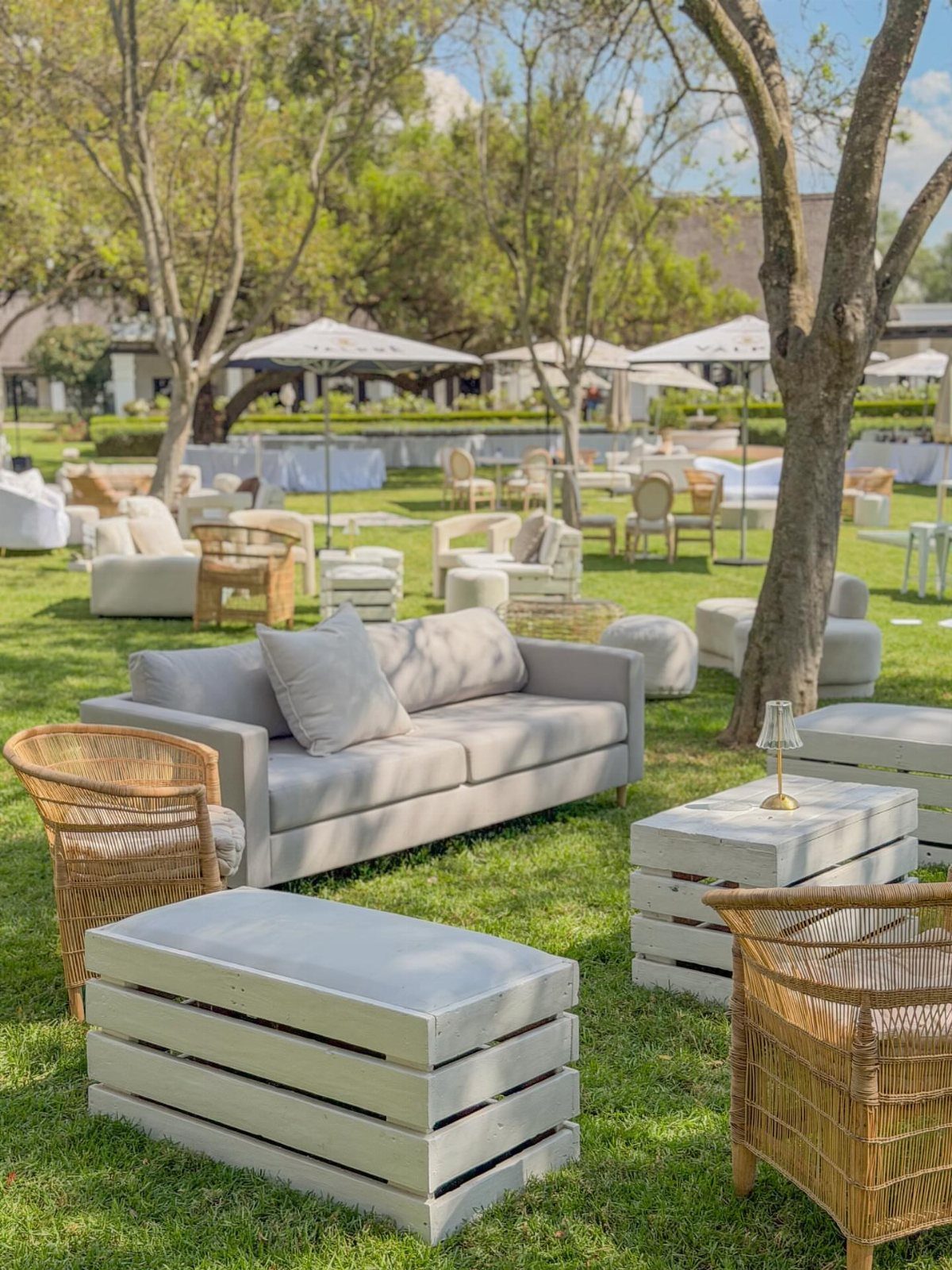 Outdoor lounge area with a grey sofa, wicker chairs, and white crate tables.