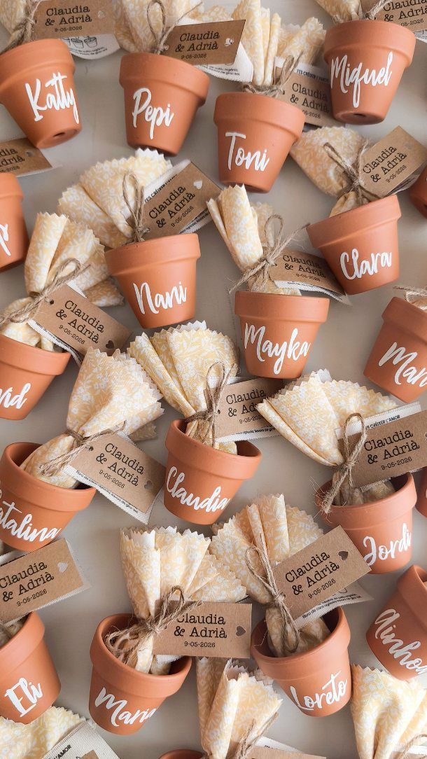 Terracotta pots with napkins and personalized name tags for wedding guest seating.